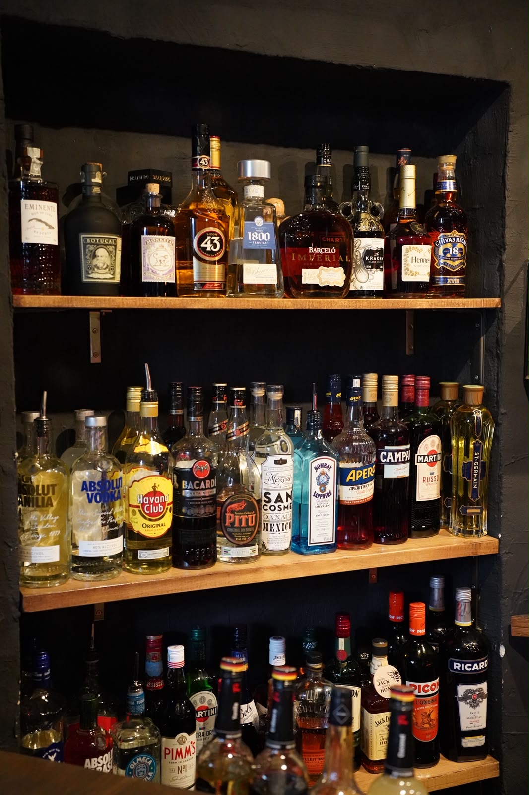 Spirituosen in drei Regalreihen in einer Wandnische hinter der Bar